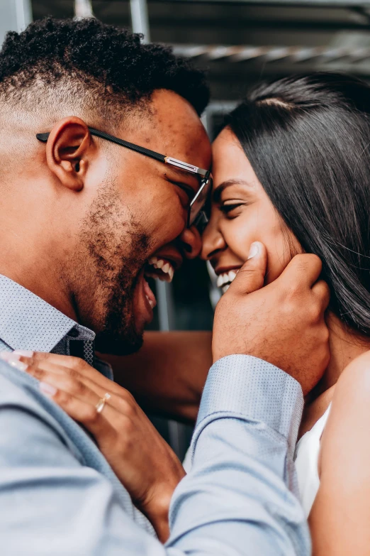 a woman hugs a man's face as he smiles and laughs