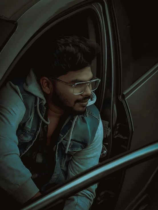 an indian man wearing a vest and glasses sitting in a car