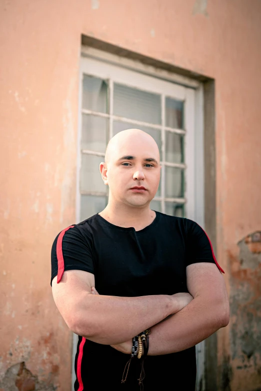 a bald headed man standing in front of a window