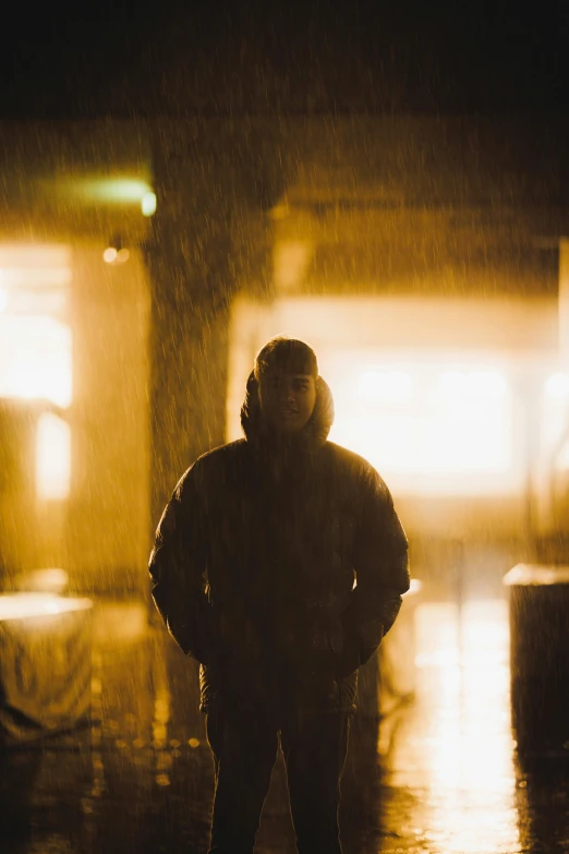 a man in a raincoat standing at night with his hands on his hips