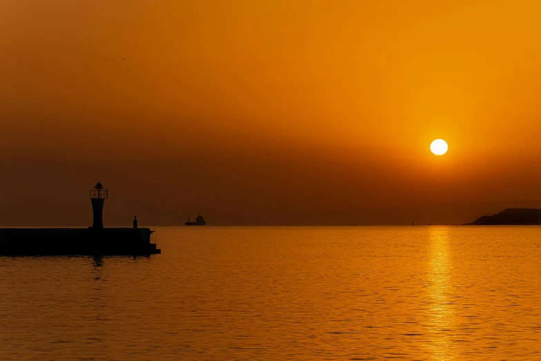 sun setting over the ocean with small boats in the distance