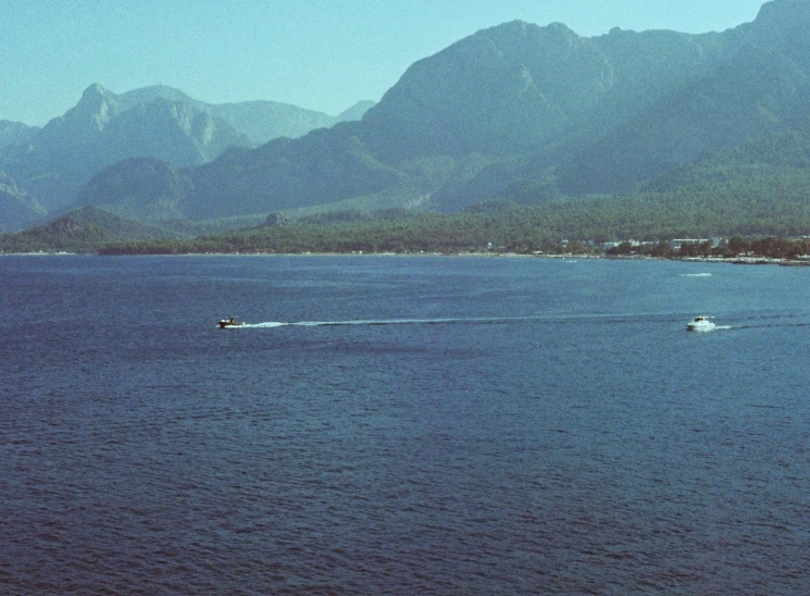 a boat traveling across the water in front of mountains