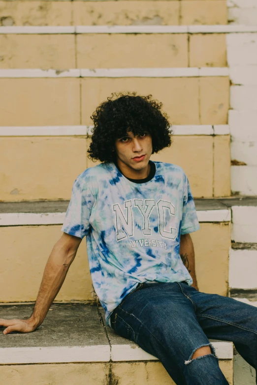 young man with large afro sitting in front of a stack of stairs