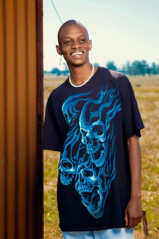 man with a blue shirt standing next to rusty fence