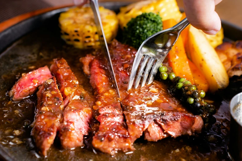 a person using tongs to cut up a piece of meat