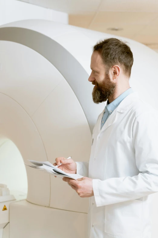 a man in white lab coat standing in front of a white mri