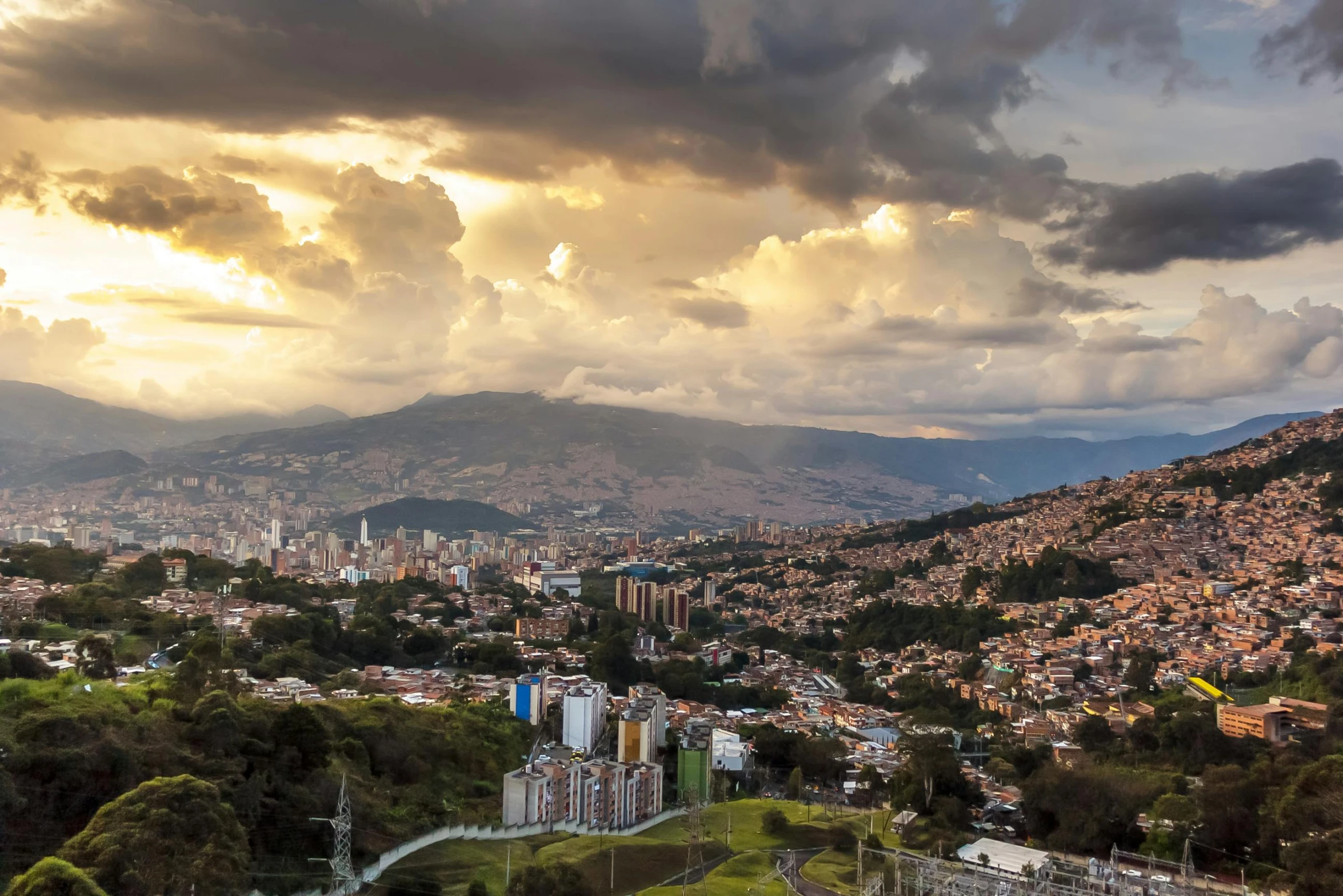 a city with mountains in the background and clouds over it