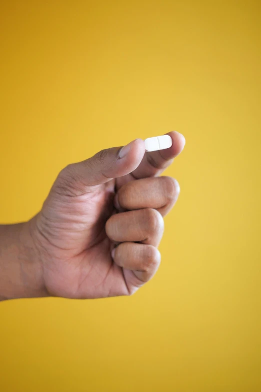 a close up s of a male hand holding a white pill