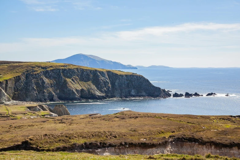 the grassy hillside is near an ocean and an island