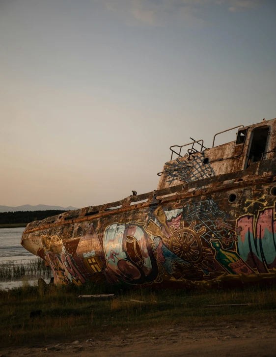 a rusted up boat next to water at dusk