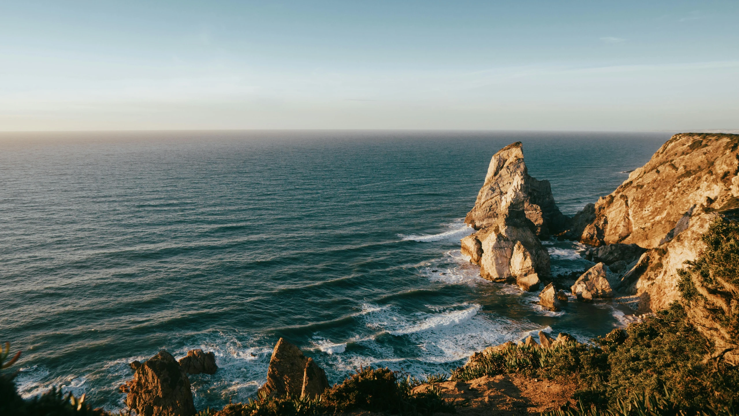 a cliff overlooks the ocean with clear blue skies