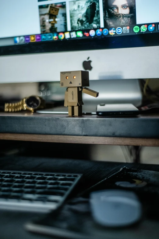 an apple computer and toy robot on desk