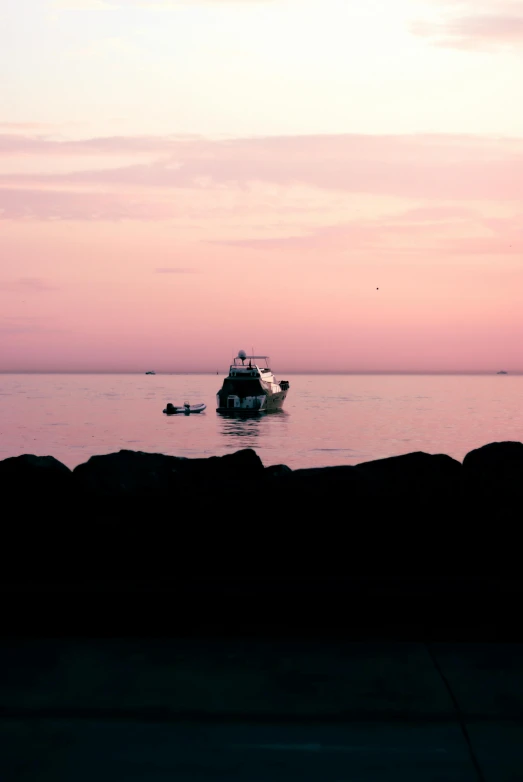 a boat sailing out into the water near some rocks