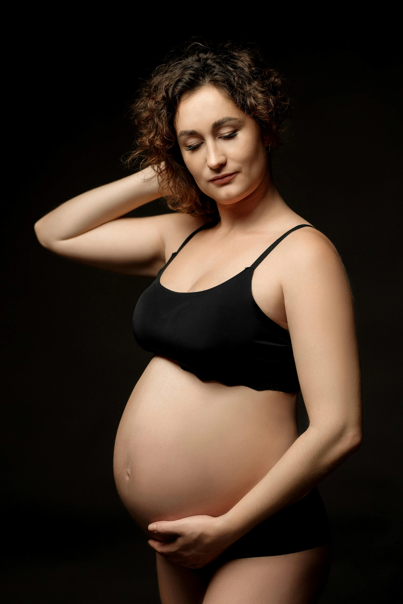 the pregnant woman poses in her black bikini for this pograph