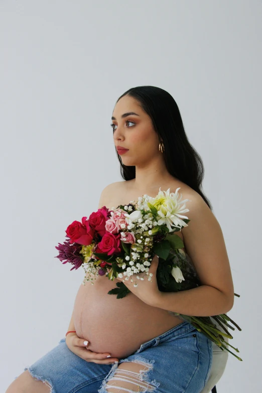 a pregnant woman holding a bouquet of flowers