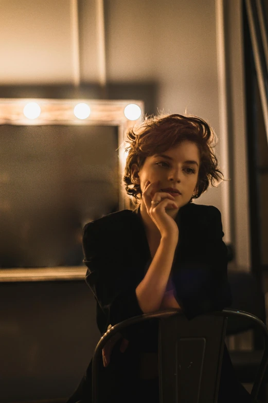 a woman sitting in a chair with her hand on her chin