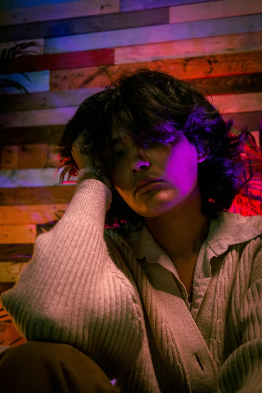 a woman sitting in front of a wooden wall