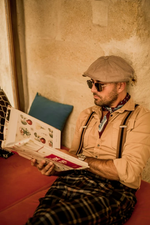 man with beard wearing shades while reading an article in his book