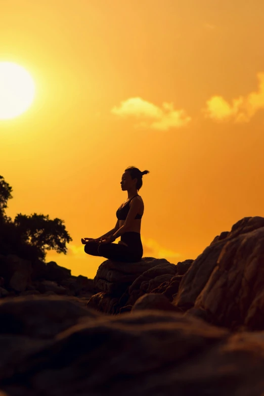 the woman sits on the rocks doing yoga