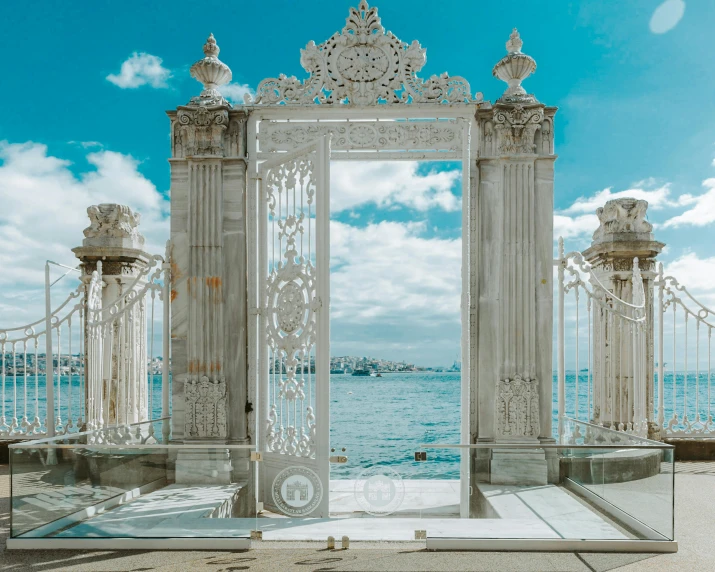 an elaborate white, wrought iron entrance to a blue ocean