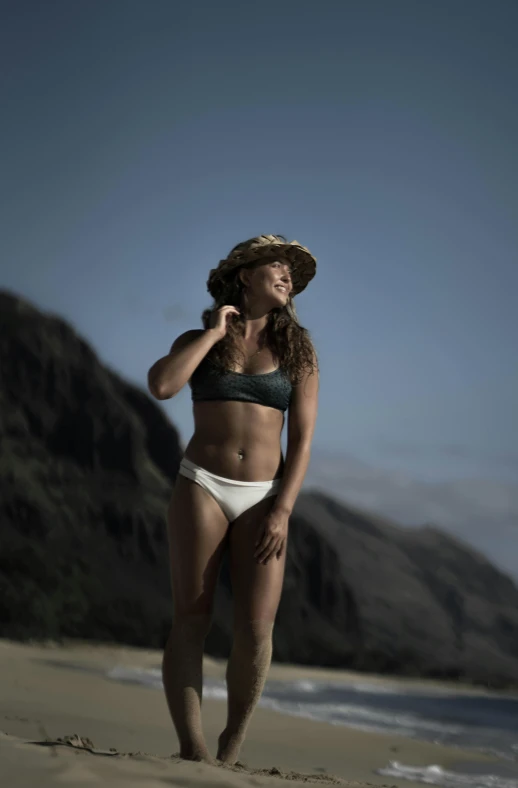 a woman with an open hat standing on the beach