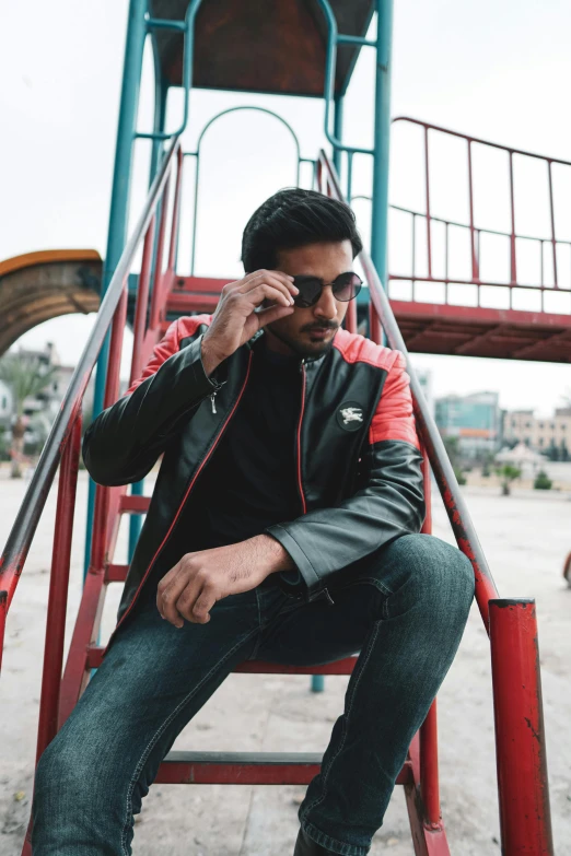 a man sits on a playground with his hands on his head