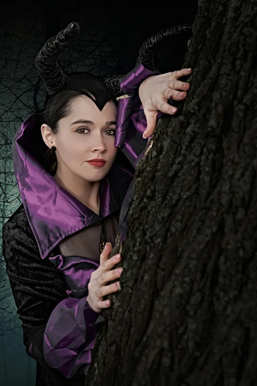 a woman is standing near a tree in costume