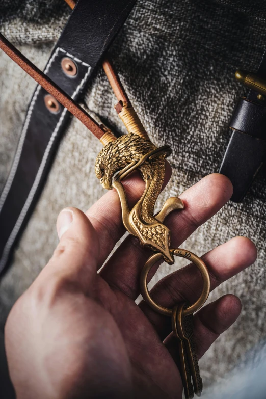 man holding gold snake hook in hand over jeans