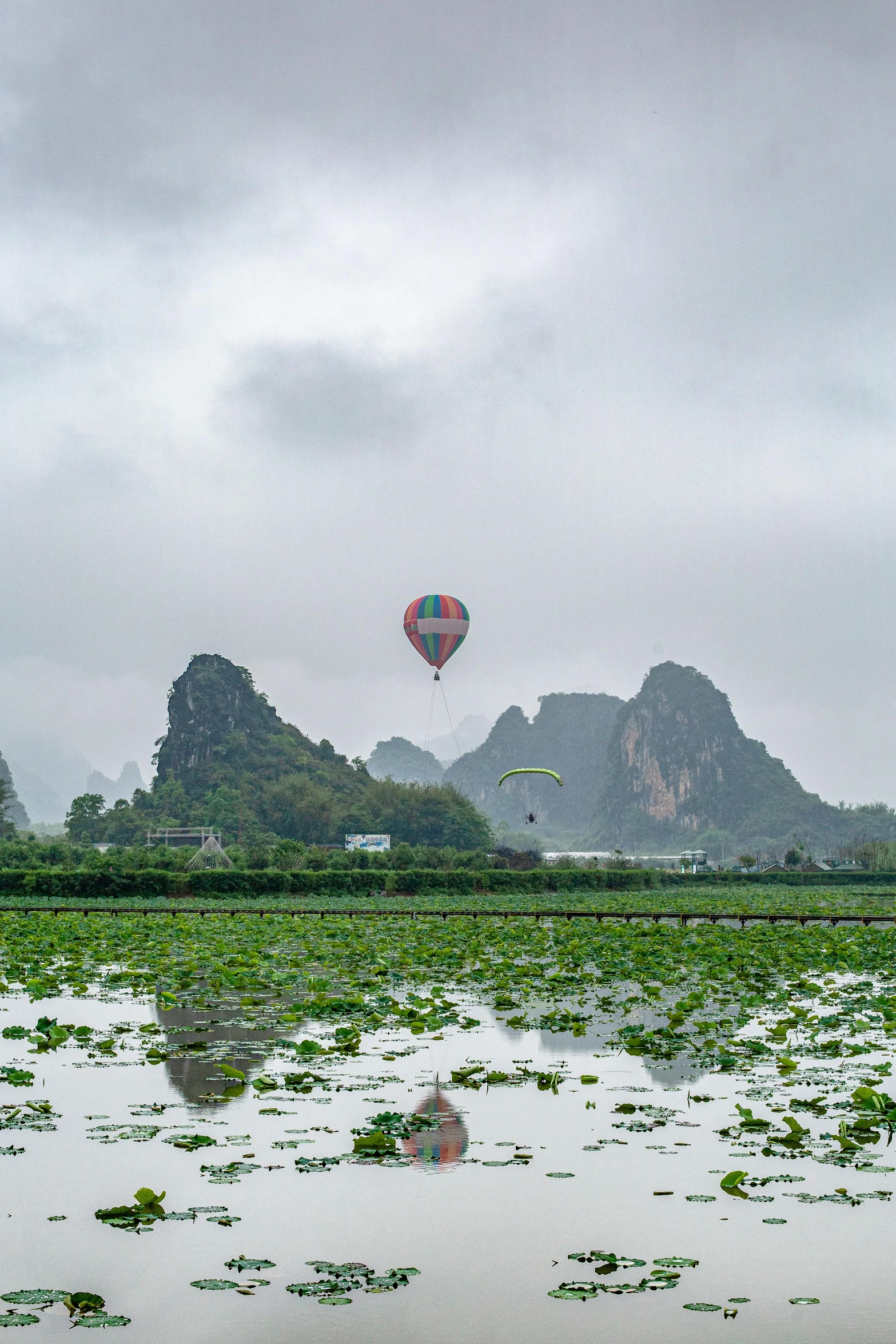 several colorful balloons fly in the sky above a lake