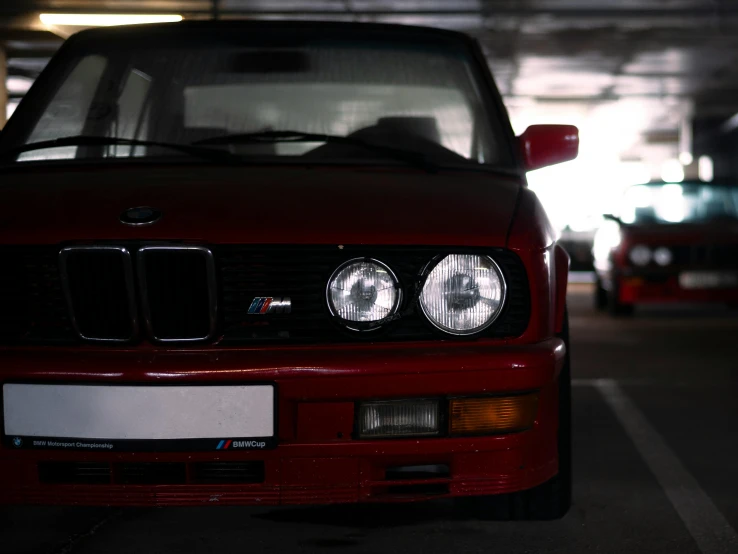 a red bmw is parked in an empty parking garage