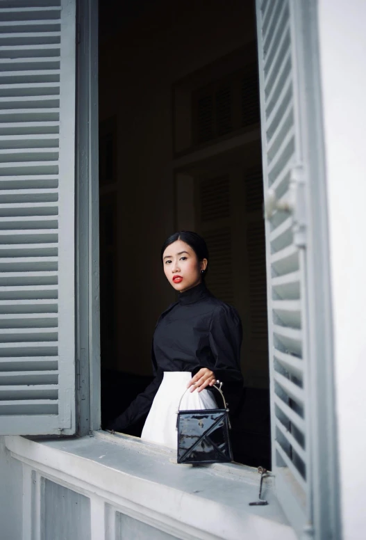 an asian woman in black, white and black looks out the window