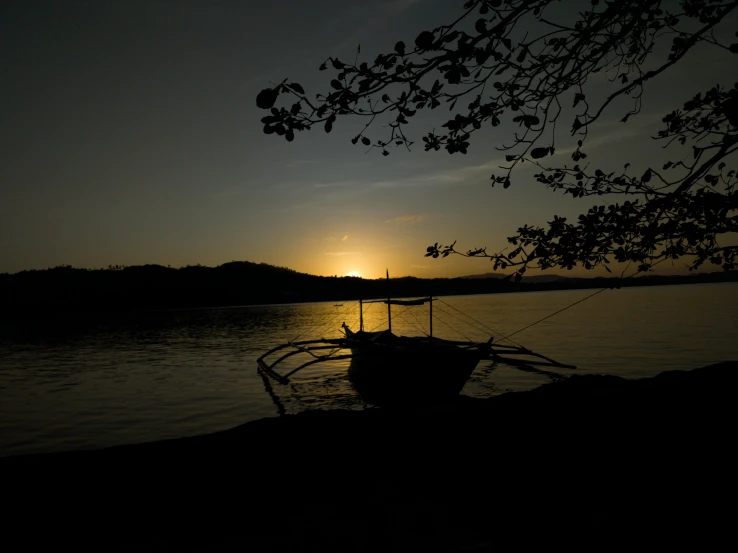 a boat sits in the calm waters as the sun rises