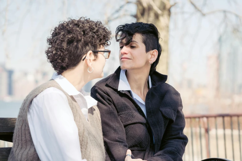 two women sitting on a bench talking and laughing