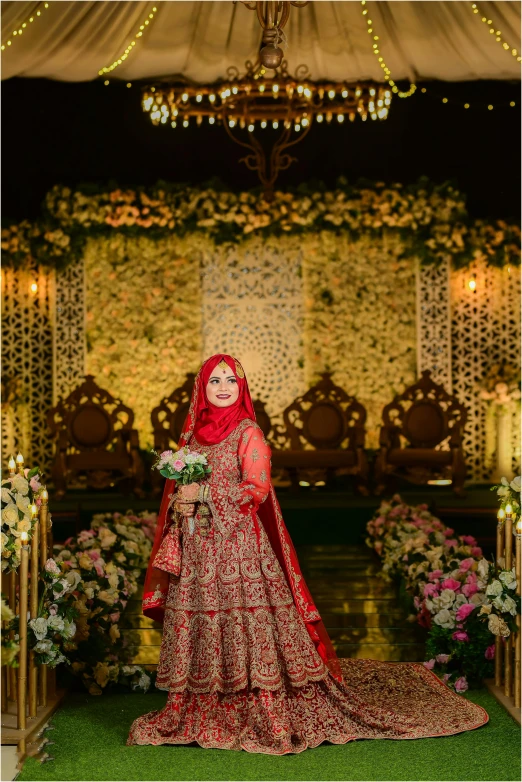 indian bride in a red and gold outfit posing for wedding pographs