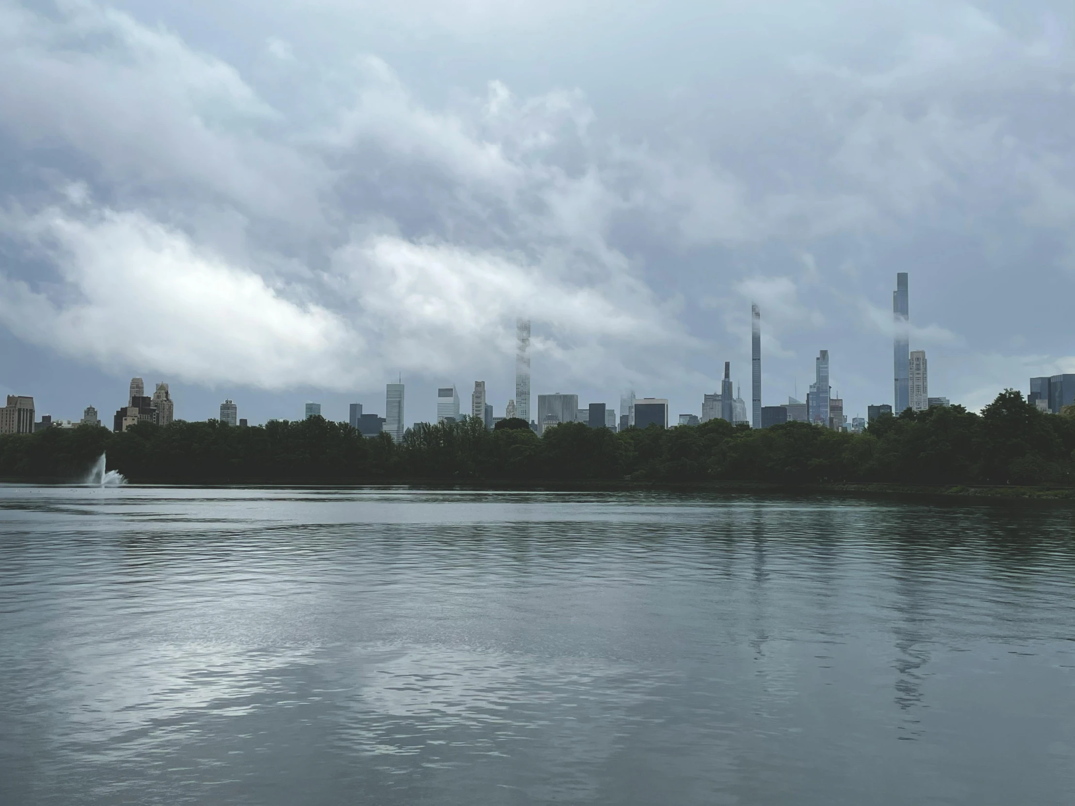 city skyline next to lake on cloudy day