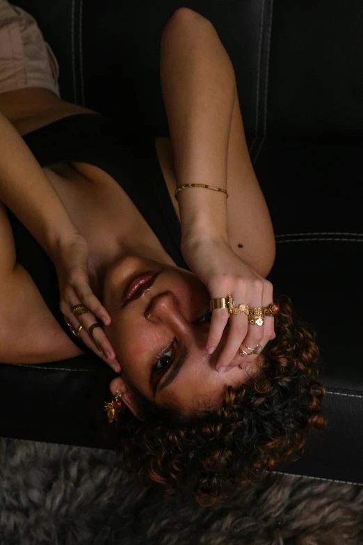 woman with rings sitting on a black chair and making a face