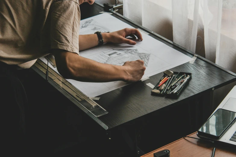 man working at desk in front of window with laptop