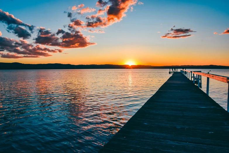 a dock with water and some clouds in the sky