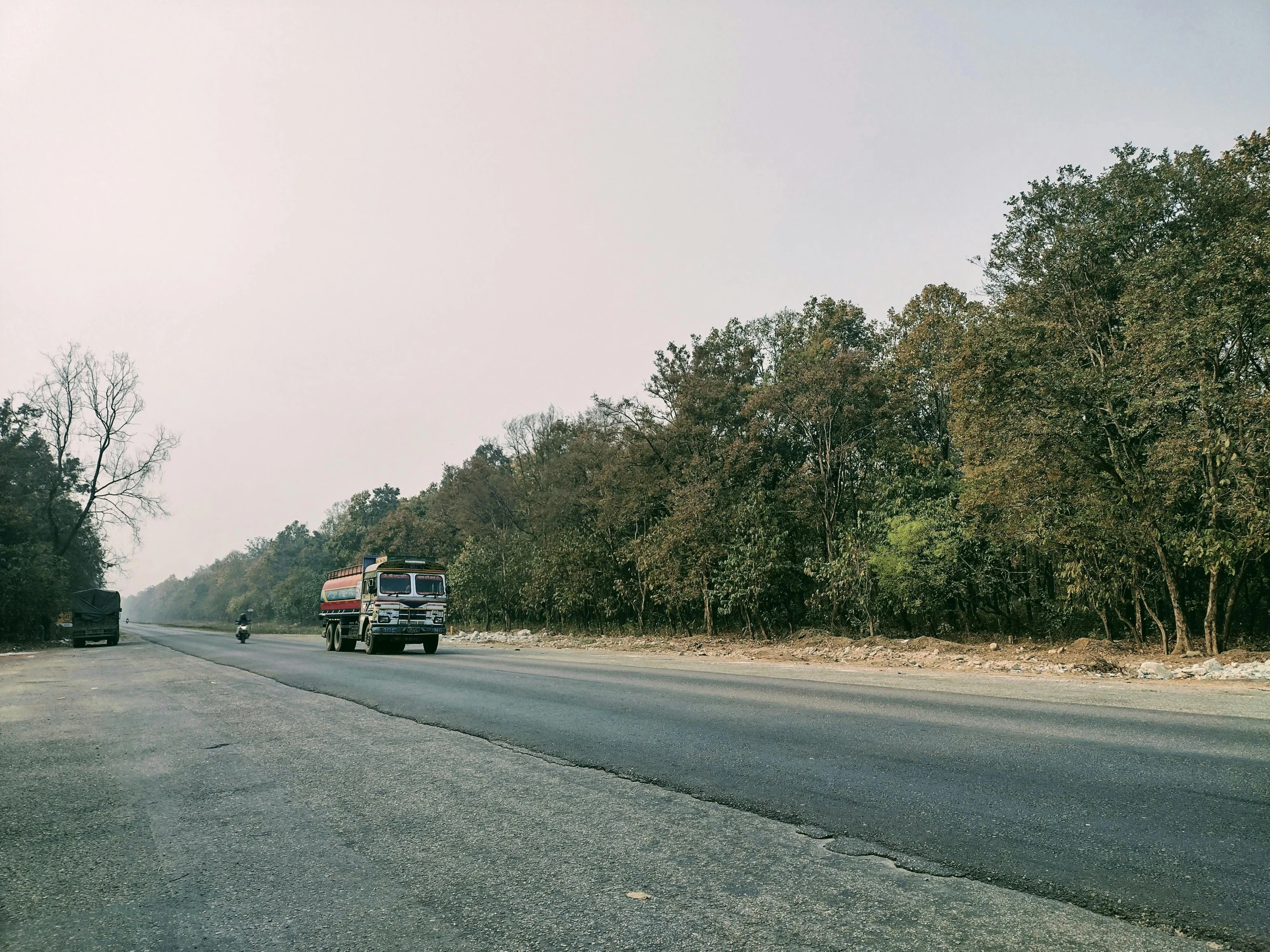 a truck and a van driving on a road with trees