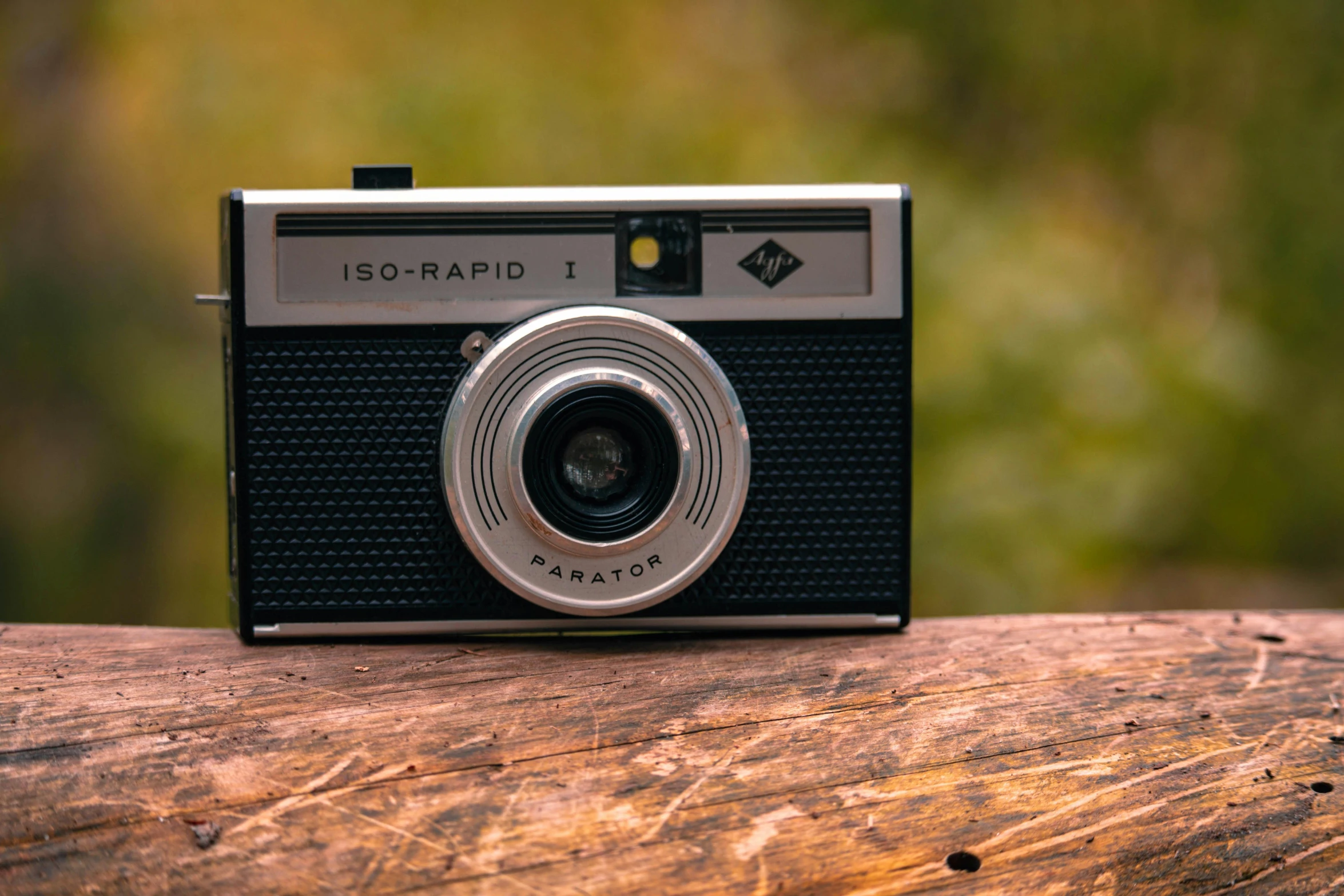 an old fashioned camera sitting on top of a piece of wood