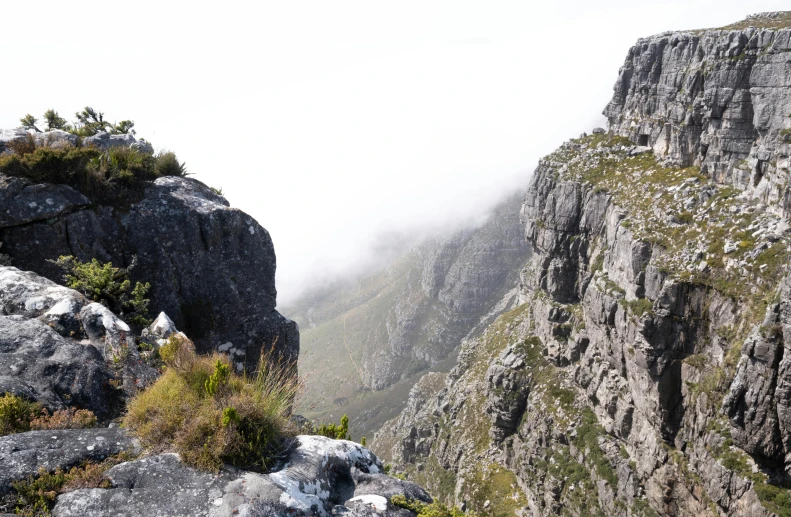 clouds hover over the rocks and mountains at the edge