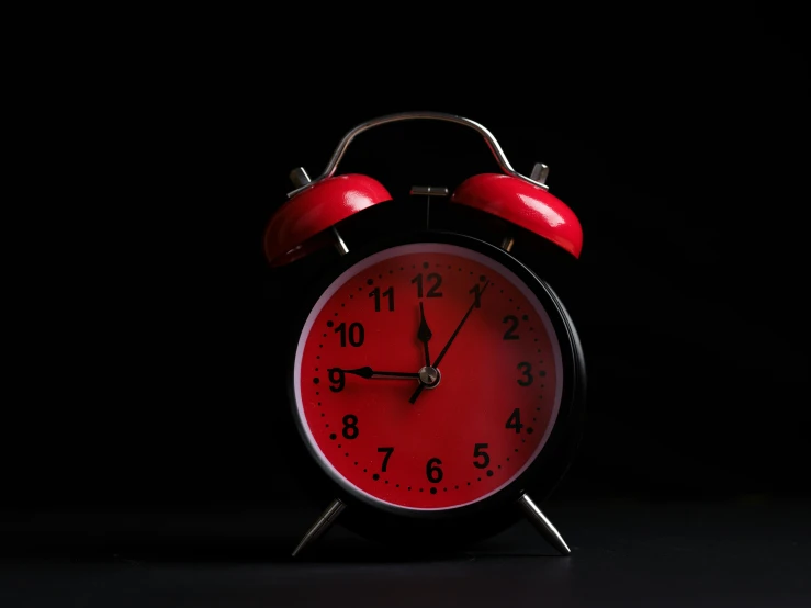 an old fashioned red alarm clock in the dark