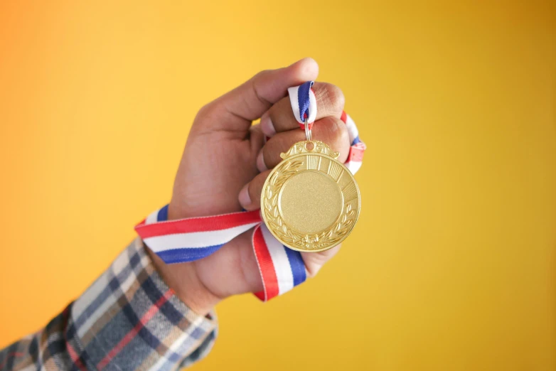 a close - up of a person holding a gold medal