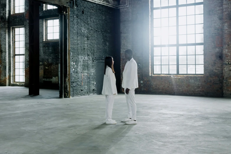 two people stand in an empty warehouse