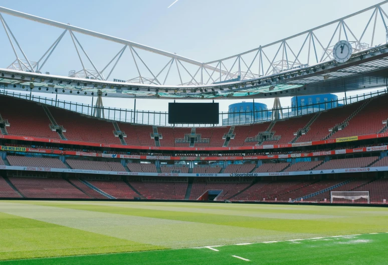 an empty stadium with a few seats and a green field