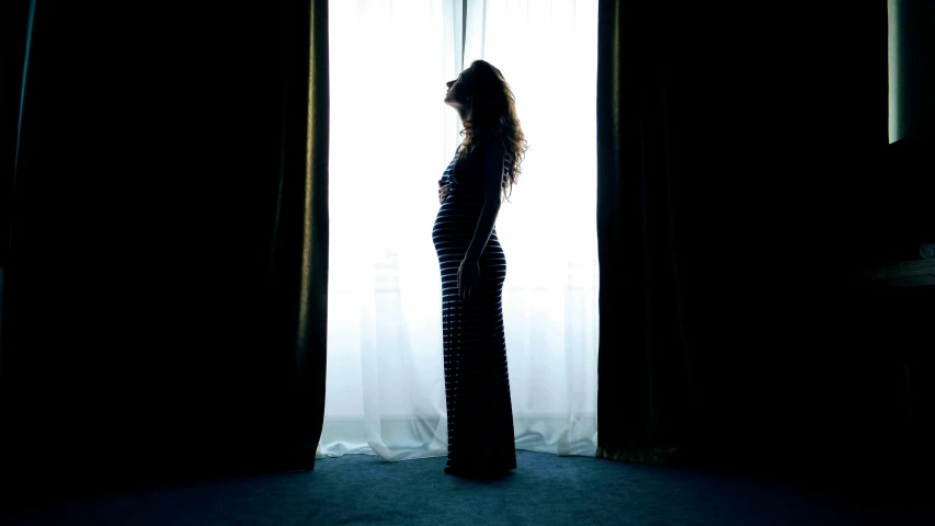 a woman in striped dress standing at window