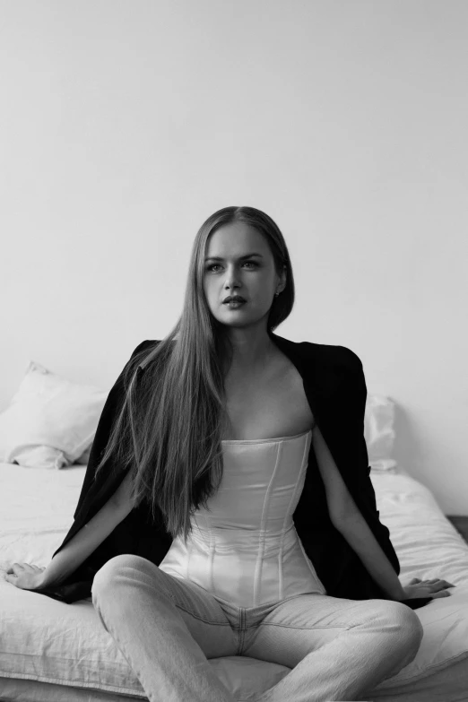 a beautiful young woman sitting on top of a bed