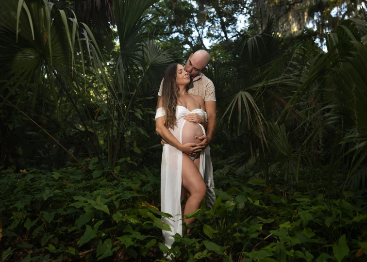 a pregnant couple kissing in the woods for a po shoot