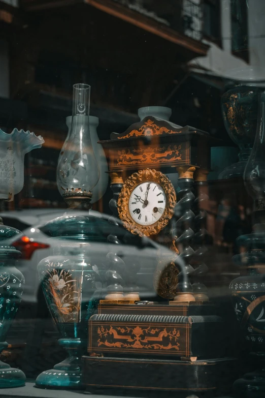 an assortment of clocks and glass vases in a shop window