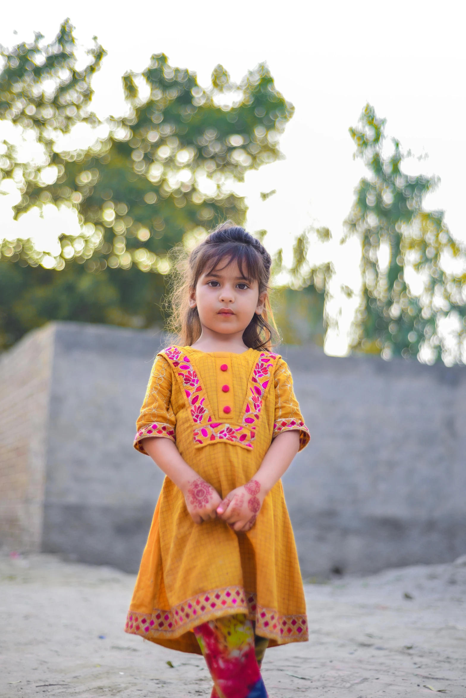 a little girl standing on the dirt near the woods